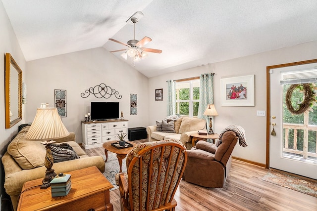 living room featuring vaulted ceiling, a textured ceiling, ceiling fan, and light wood-type flooring