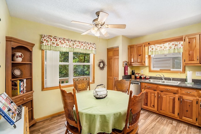 dining space featuring ceiling fan, sink, a textured ceiling, and light wood-type flooring