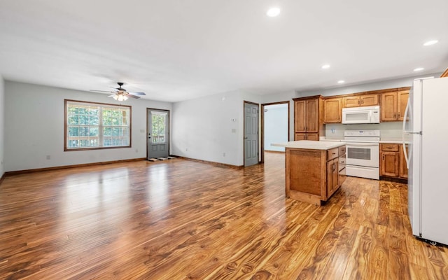 kitchen with light hardwood / wood-style flooring, ceiling fan, white appliances, and a center island