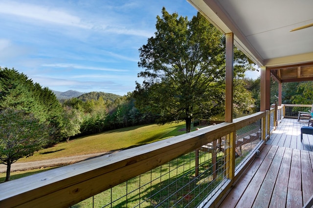 wooden deck featuring a mountain view and a lawn