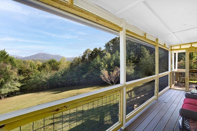 wooden deck featuring a mountain view and a lawn