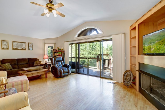 living room featuring built in shelves, ceiling fan, light hardwood / wood-style flooring, and lofted ceiling