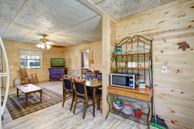 dining space featuring wood walls and ceiling fan