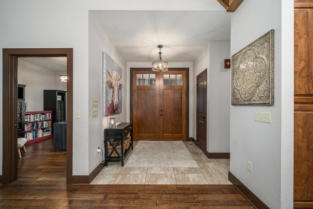 foyer entrance featuring a notable chandelier, light wood-type flooring, and baseboards