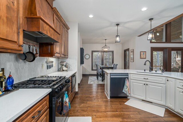 kitchen with dark wood-style flooring, light countertops, backsplash, a sink, and black appliances