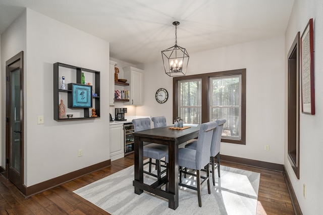 dining room with a notable chandelier, beverage cooler, baseboards, and dark wood-style flooring