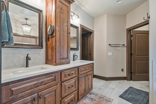 bathroom with tasteful backsplash, a sink, baseboards, and wood finished floors