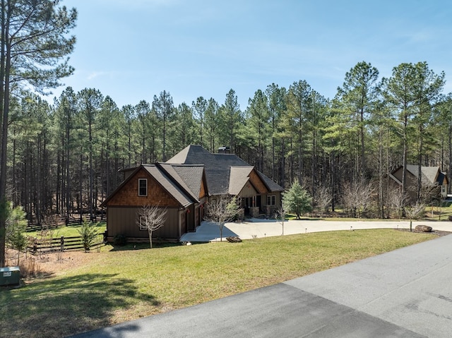 view of property exterior featuring fence, a wooded view, and a yard