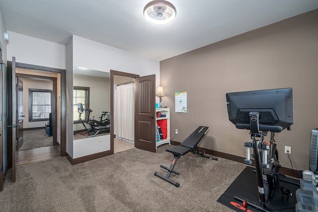 workout room with carpet flooring, a textured ceiling, and baseboards