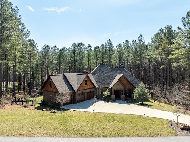 view of front of home featuring an attached garage, concrete driveway, a front yard, and fence