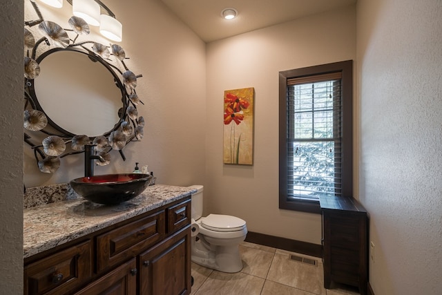 half bath featuring visible vents, toilet, vanity, tile patterned flooring, and baseboards