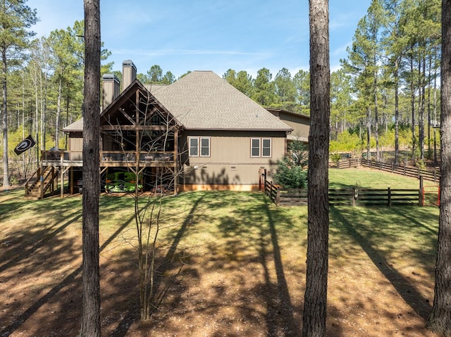 back of property featuring fence, stairs, roof with shingles, a lawn, and a chimney