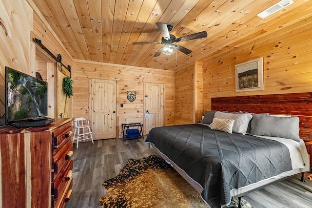 bedroom with dark wood-type flooring, wood walls, a barn door, and wooden ceiling