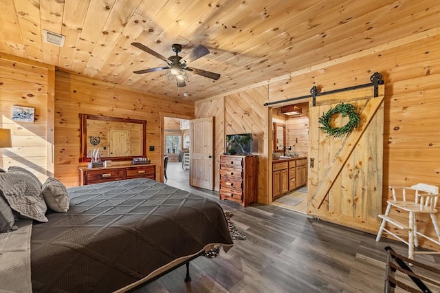 bedroom featuring hardwood / wood-style floors, wooden walls, wooden ceiling, and a barn door