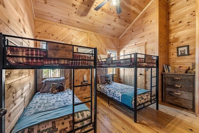 bedroom featuring light wood-type flooring, wooden ceiling, vaulted ceiling, and wood walls