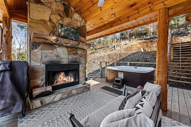 view of patio / terrace featuring a hot tub, a wooden deck, and an outdoor stone fireplace