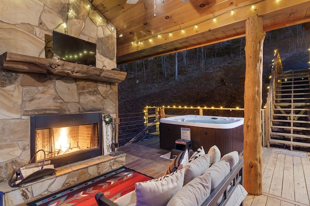 exterior space with a hot tub and an outdoor living space with a fireplace