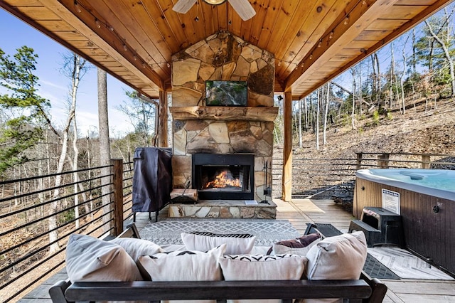 view of patio with a wooden deck, a hot tub, an outdoor living space with a fireplace, and ceiling fan