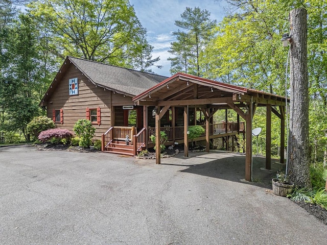 view of front facade with roof with shingles, a carport, and aphalt driveway