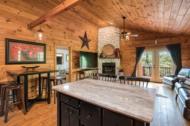 kitchen featuring wood ceiling, vaulted ceiling, wood walls, and open floor plan