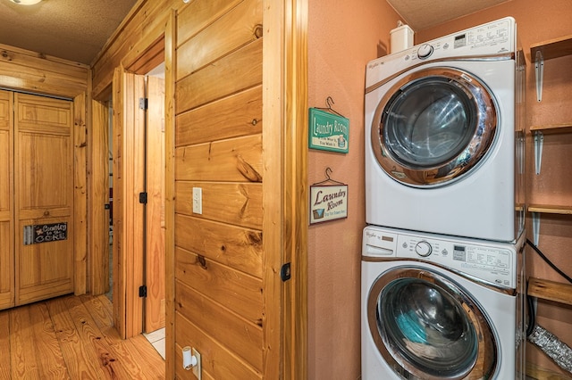 washroom with stacked washer and clothes dryer, light wood-type flooring, a textured ceiling, and laundry area
