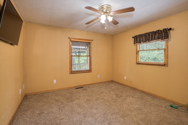 carpeted spare room featuring baseboards, ceiling fan, a textured ceiling, and visible vents