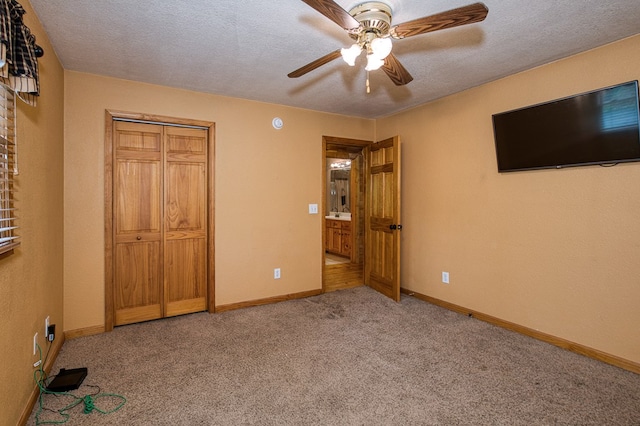 unfurnished bedroom featuring carpet flooring, ceiling fan, a textured ceiling, baseboards, and a closet