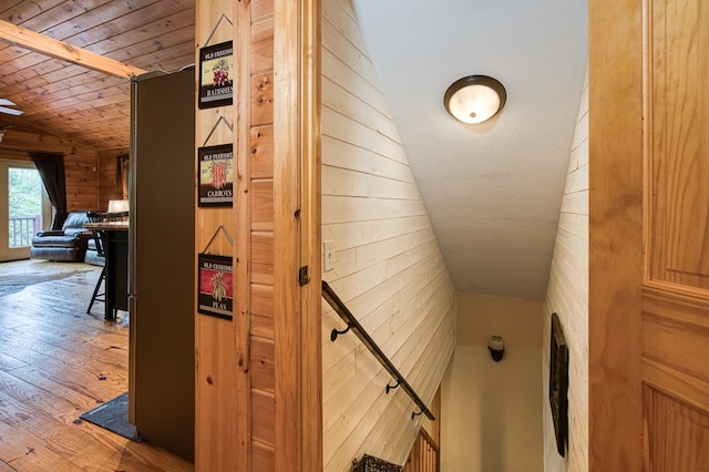stairway featuring wood walls, lofted ceiling, hardwood / wood-style flooring, and wooden ceiling
