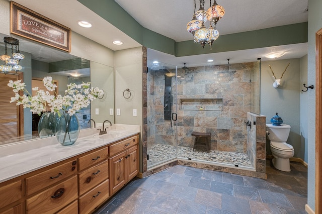 bathroom featuring vanity, toilet, baseboards, stone finish floor, and a shower stall