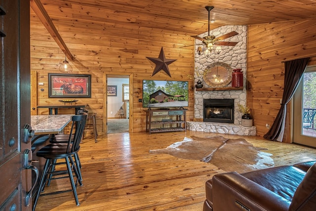 living room featuring wood walls, wooden ceiling, hardwood / wood-style flooring, a ceiling fan, and vaulted ceiling