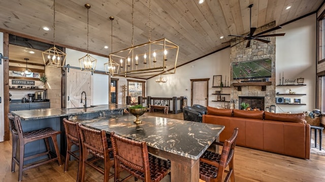 kitchen with a sink, light wood-style floors, wood ceiling, a chandelier, and a stone fireplace