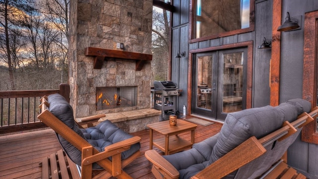 deck at dusk featuring a stone fireplace, grilling area, and french doors