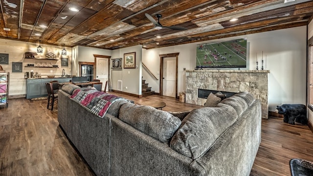 living room featuring stairway, a fireplace, dark wood finished floors, ceiling fan, and baseboards