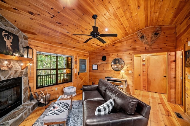 living room with a stone fireplace, wooden walls, lofted ceiling, wood ceiling, and light wood-type flooring