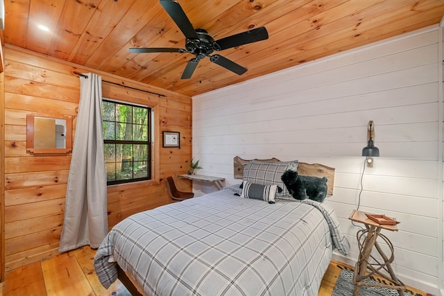 bedroom with ceiling fan, wooden walls, wood ceiling, and light hardwood / wood-style floors