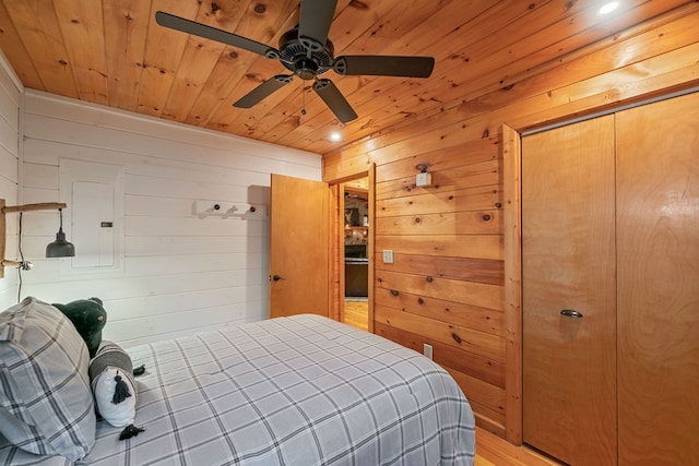 bedroom with ceiling fan, wooden walls, wood ceiling, and light wood-type flooring