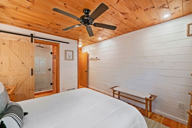 bedroom featuring hardwood / wood-style floors, wooden ceiling, a barn door, and wood walls