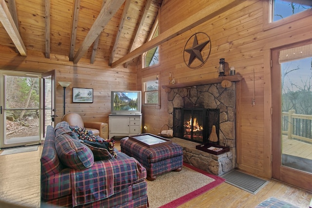 living room featuring wood walls, wood ceiling, beamed ceiling, a fireplace, and light hardwood / wood-style floors