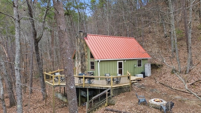 rear view of house with a wooden deck and a fire pit