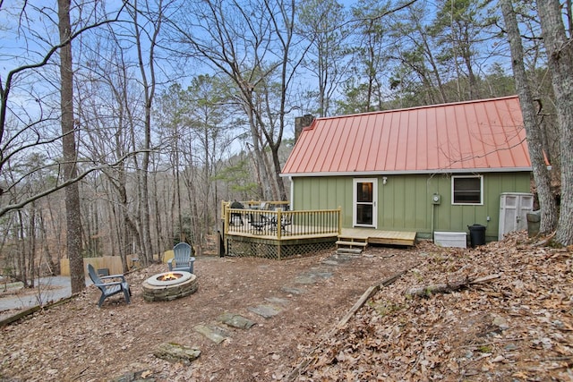 rear view of property with a wooden deck and a fire pit
