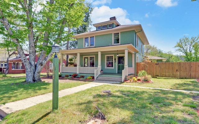 traditional style home featuring a porch, a chimney, fence, and a front lawn