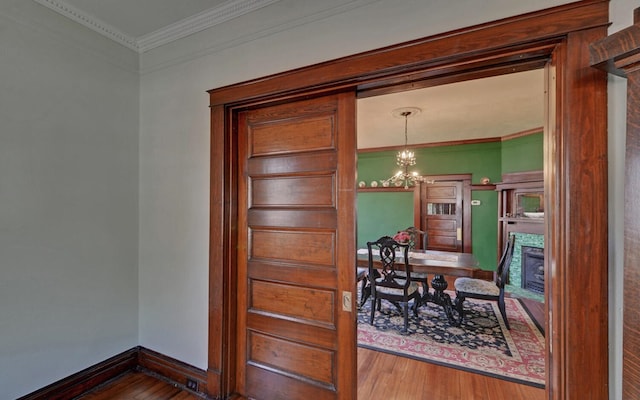 dining space featuring ornamental molding, an inviting chandelier, wood finished floors, and a fireplace
