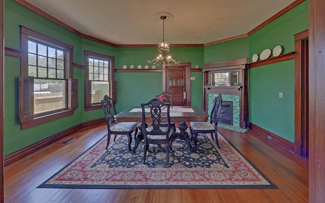 dining area with a chandelier, wood finished floors, ornamental molding, and visible vents