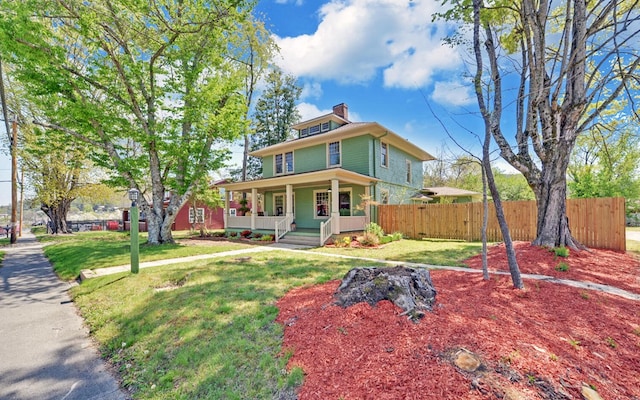 american foursquare style home featuring a front yard, a porch, fence, and a chimney
