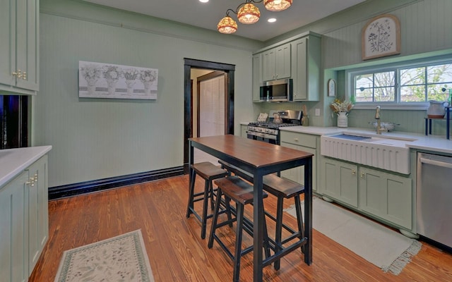 kitchen featuring green cabinets, appliances with stainless steel finishes, a sink, and light wood-style floors