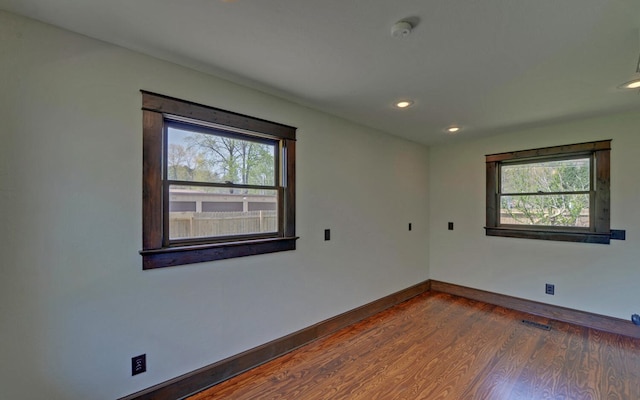 unfurnished room with visible vents, baseboards, wood finished floors, and a healthy amount of sunlight