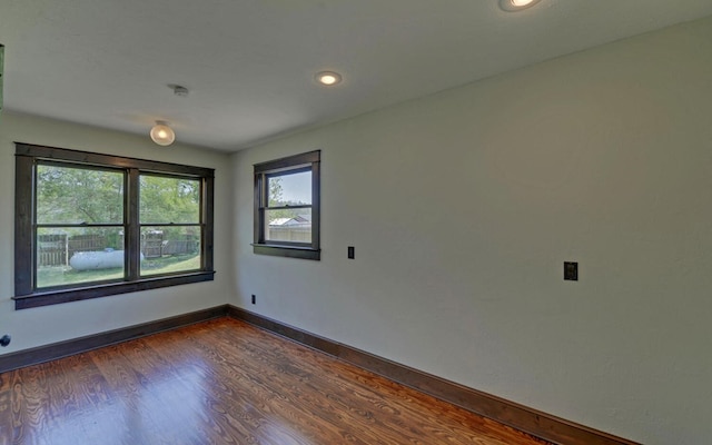 spare room featuring recessed lighting, dark wood-style flooring, and baseboards