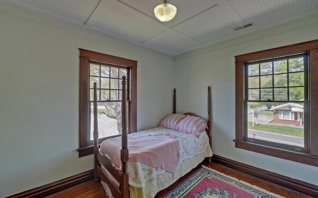 bedroom featuring baseboards, multiple windows, and dark wood finished floors