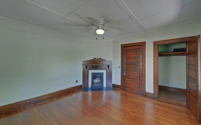 unfurnished living room featuring a fireplace with flush hearth, wood finished floors, ceiling fan, and baseboards