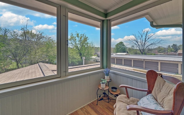 sunroom featuring crown molding, wood finished floors, and wood walls